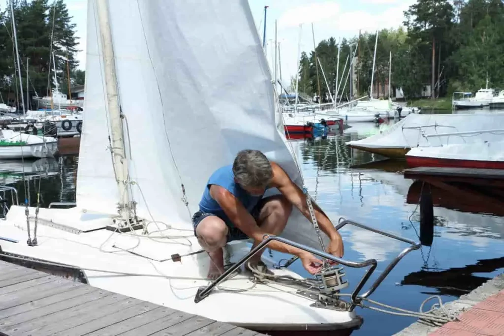 Yachtman réparant un voilier dans une marina, métier en Y mêlant technique, navigation et passion pour la mer dans un cadre serein.