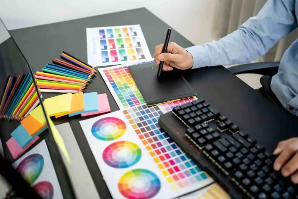 Bureau de designer avec palette de couleurs, color wheels et swatches pour création visuelle.