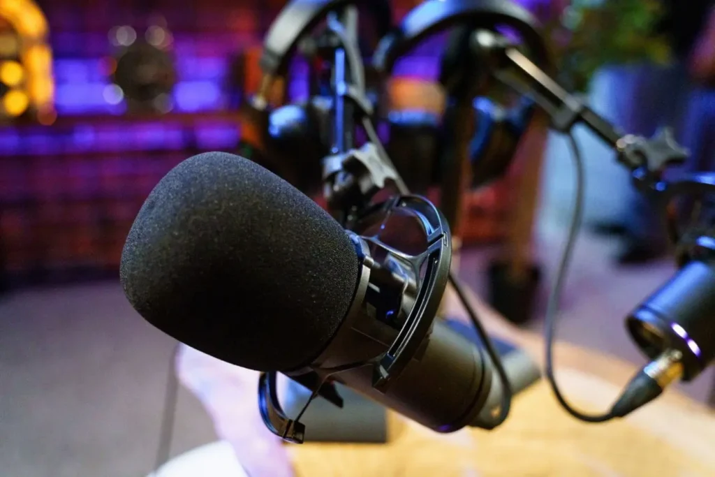 Gros plan sur micro noir avec mousse dans studio éclairé, reflet de l’univers du podcast et de la création audio
