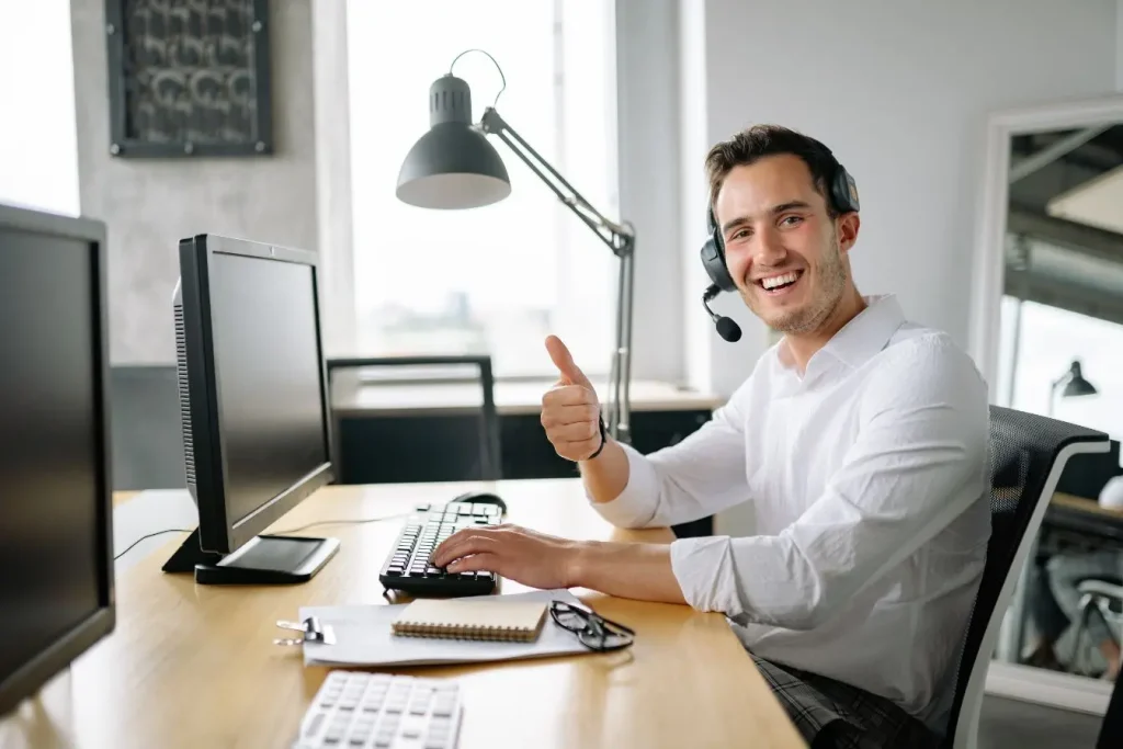 Bureau moderne avec employé en casque micro donnant un pouce levé représentant la production de UGC contenu généré par les utilisateurs.