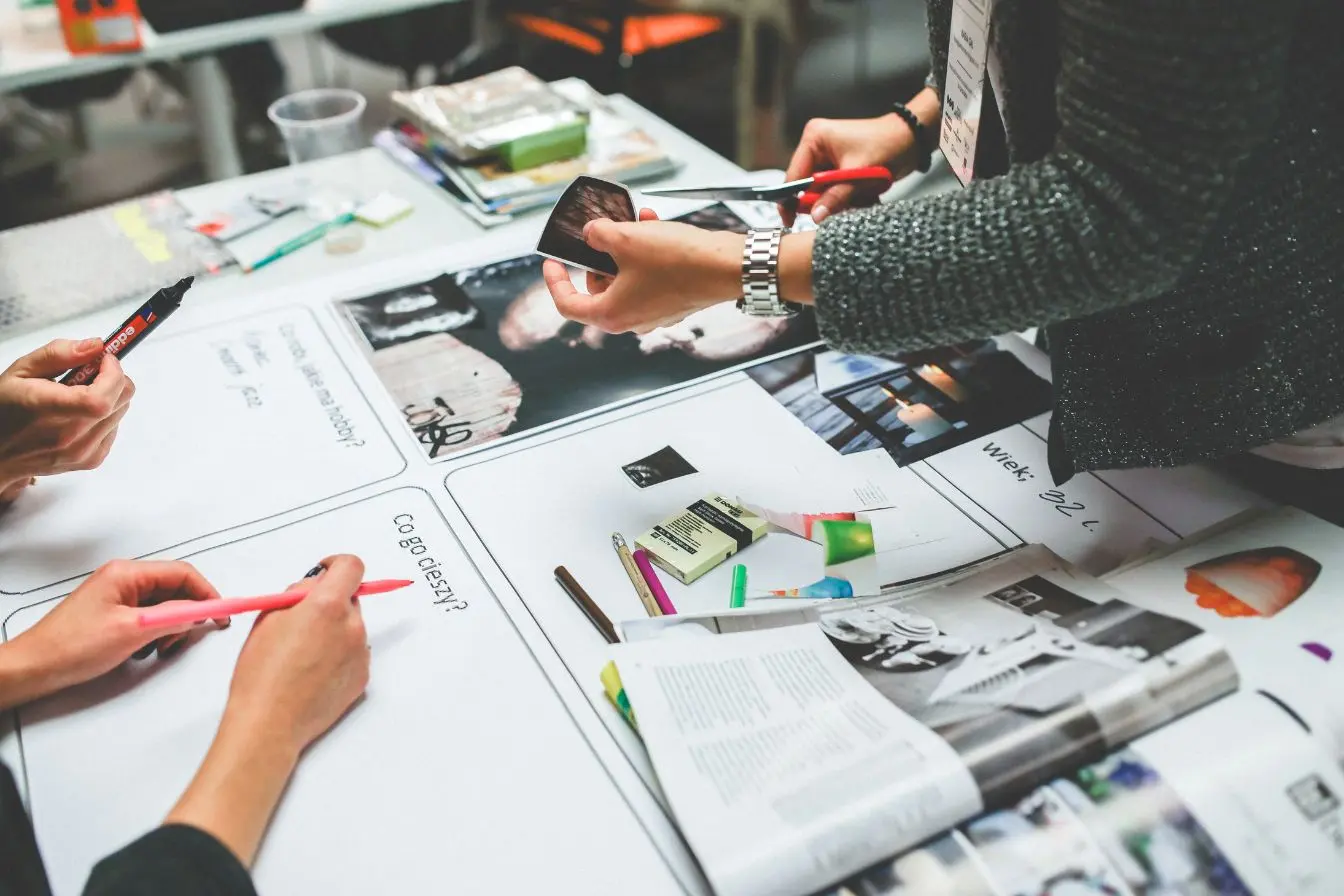 Groupe en atelier créatif découpant images et écrivant sur fiches, image illustrant l’affiliation marketing et la création de contenus collaboratifs.