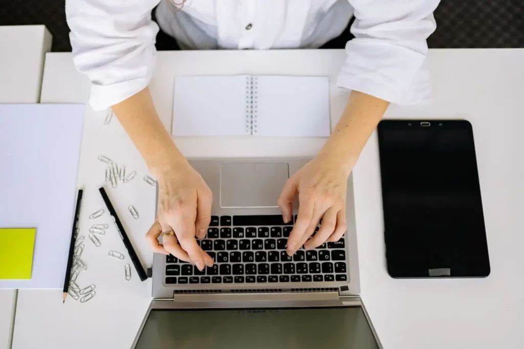 Vue de dessus d’un bureau avec ordinateur portable et fournitures, image illustrant le travail de copywriting dans un cadre organisé et créatif.