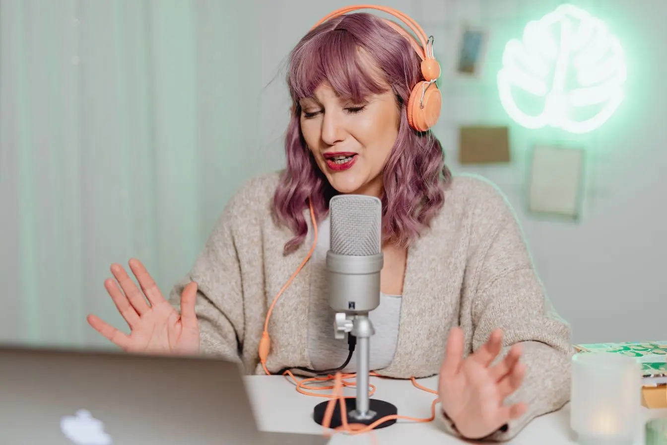 Personne aux cheveux violets avec casque orange parlant au micro, image illustrant la différence entre micro-influenceurs proches et macro-influenceurs puissants.