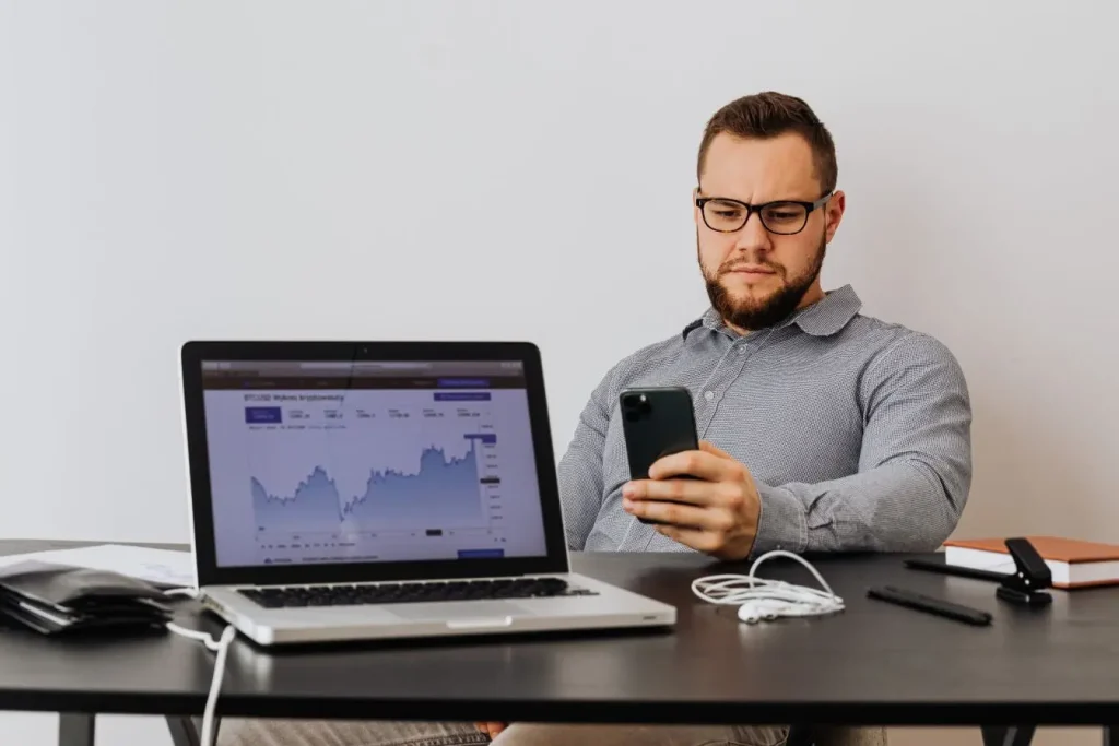 Personne analysant données de performance sur smartphone et laptop, image illustrant la mesure du ROI d’une campagne marketing grâce aux indicateurs financiers.