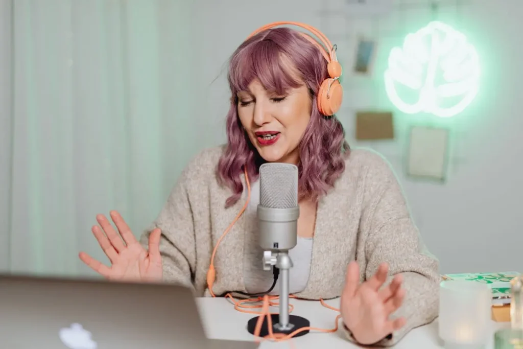 Gros plan sur personne avec casque orange et micro argenté, ambiance verte et néon feuille, image d’un podcast immersif.