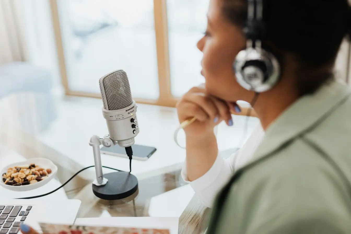 Personne avec casque devant micro Samson G Track Pro, ambiance lumineuse, image d’un podcast moderne en pleine session d’enregistrement.