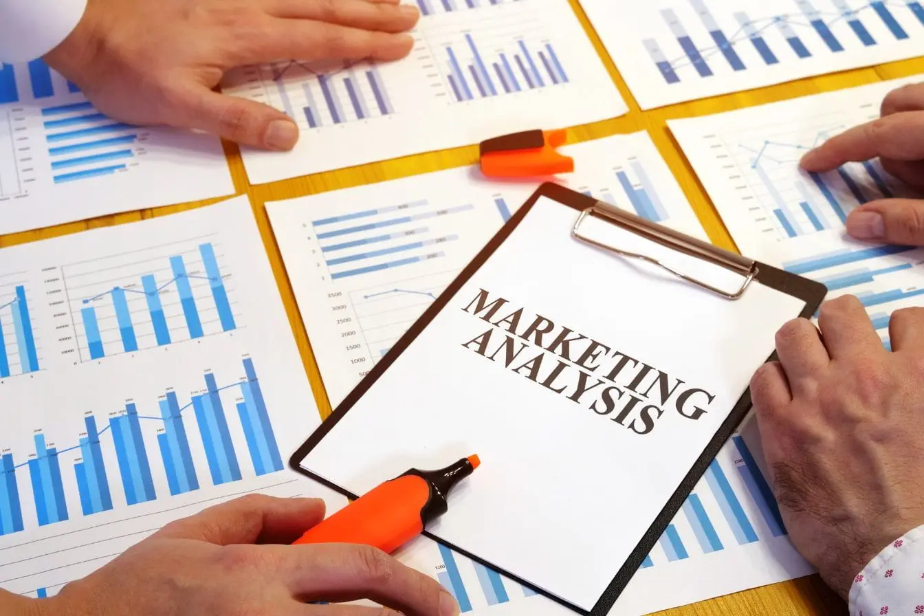 Table en bois avec graphiques marketing et feuille centrale illustrant le taux de conversion analysé en équipe pour optimiser résultats digitaux