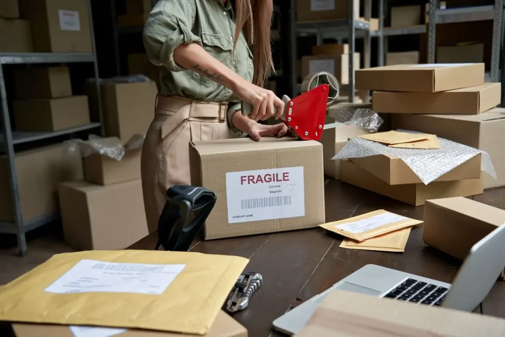 Personne scellant une boîte de vêtements avec ruban rouge, représentant la vente en dropshipping et la logistique e‑commerce