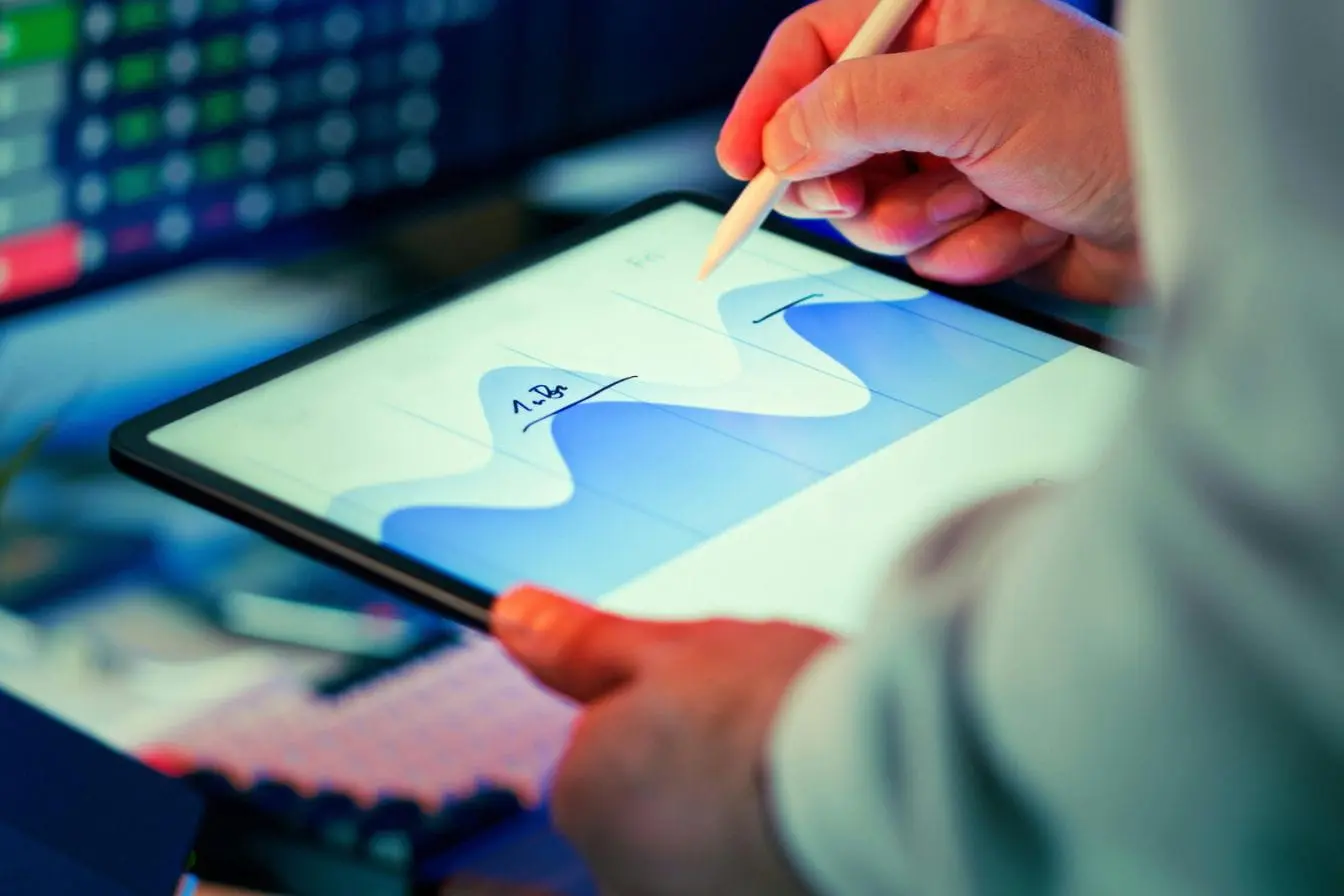Personne utilisant stylet sur tablette affichant courbes bleues, image illustrant le Data Storytelling pour donner vie aux données.
