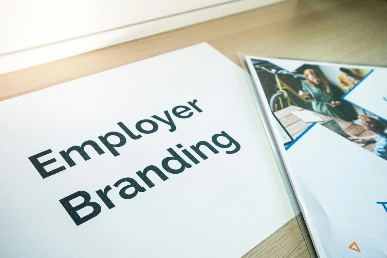 Document employer branding posé sur bureau avec magazine montrant collaborateurs, image d’une stratégie valorisant identité et attractivité d’entreprise.