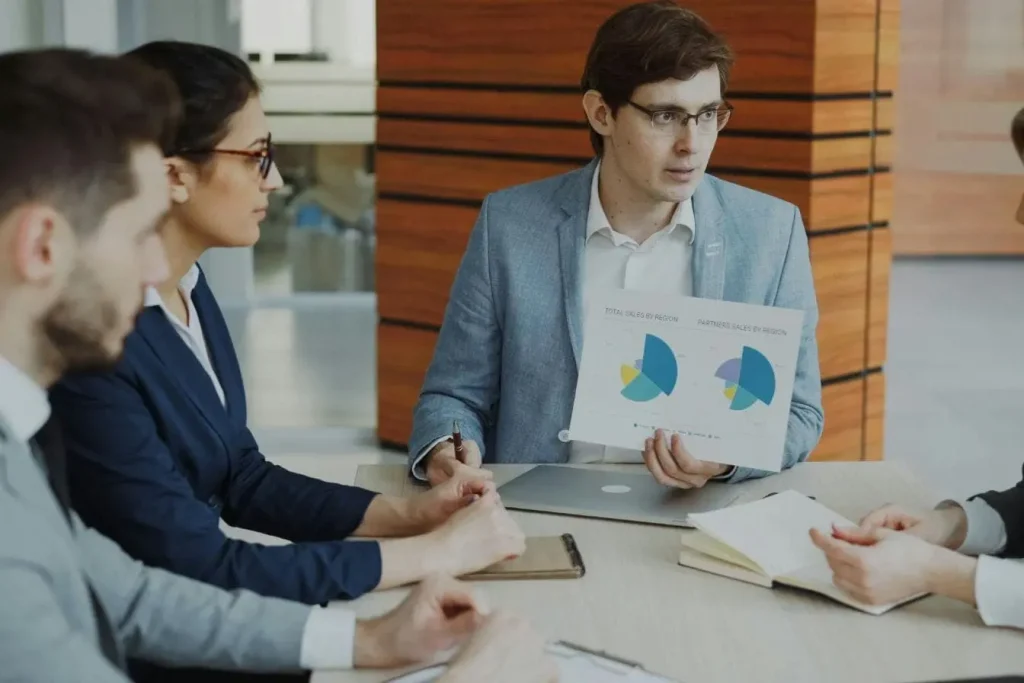 Groupe en réunion autour d’une table, image illustrant le Data Storytelling transformant des graphiques en récit clair pour guider les décisions.