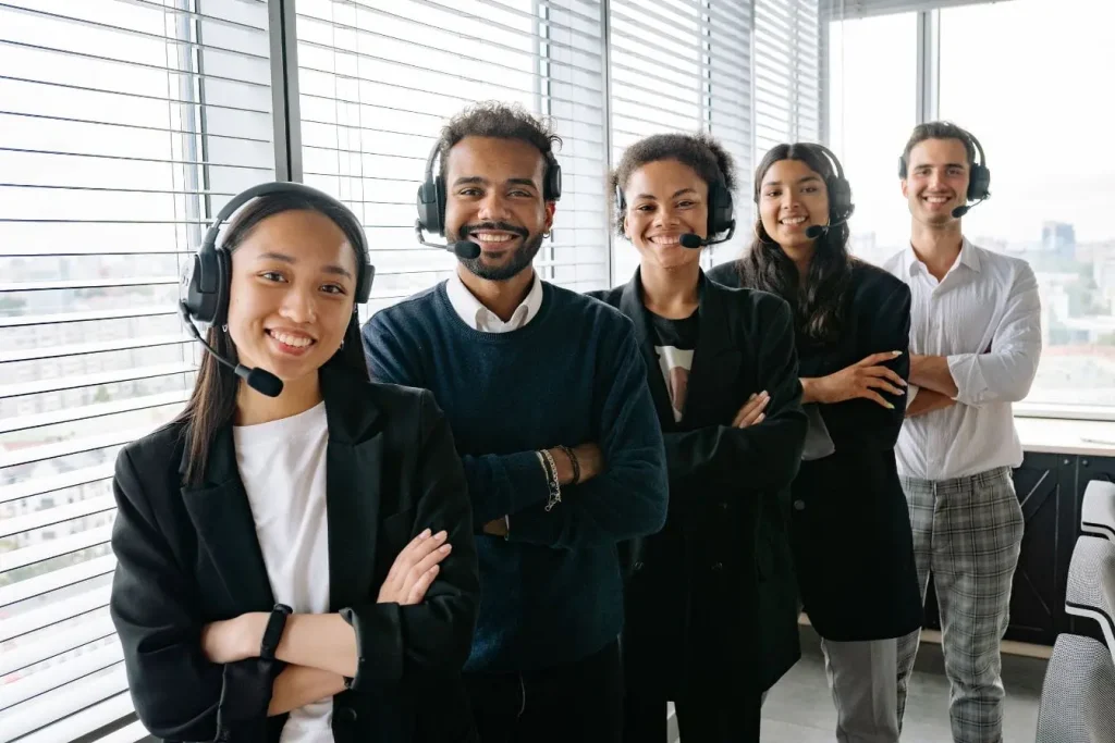 Équipe en casques micro debout dans bureau moderne, image d’une marque employeur qui valorise professionnalisme et communication.