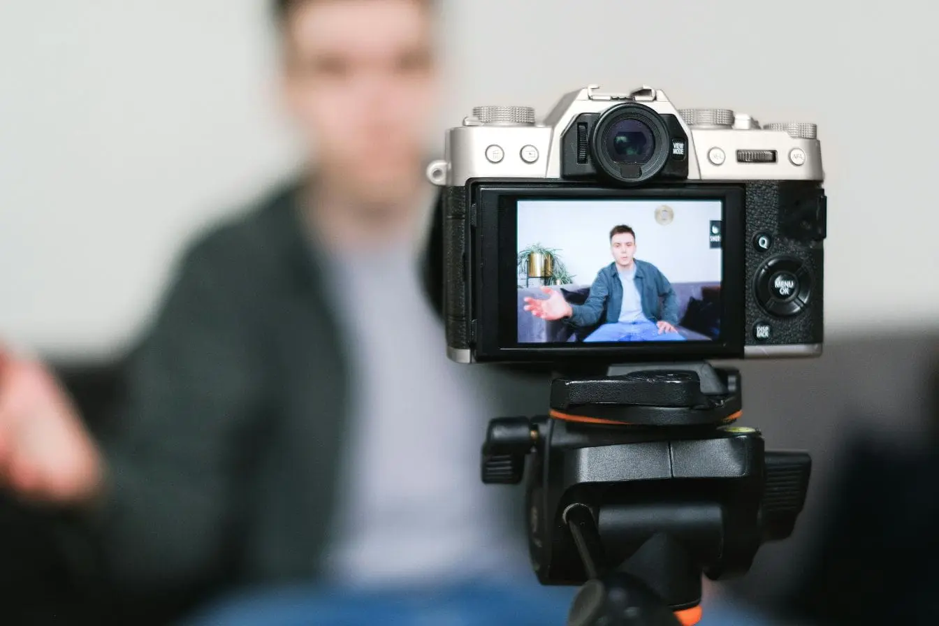 Caméra sur trépied filmant une personne en intérieur, image illustrant la création de contenu vidéo et la possibilité de monétiser un livestream.