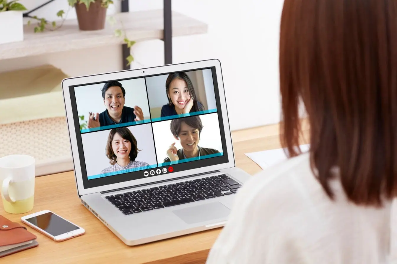 Personne assise devant un ordinateur en visioconférence avec quatre collègues, illustrant la gestion d’une équipe à distance et la collaboration numérique.