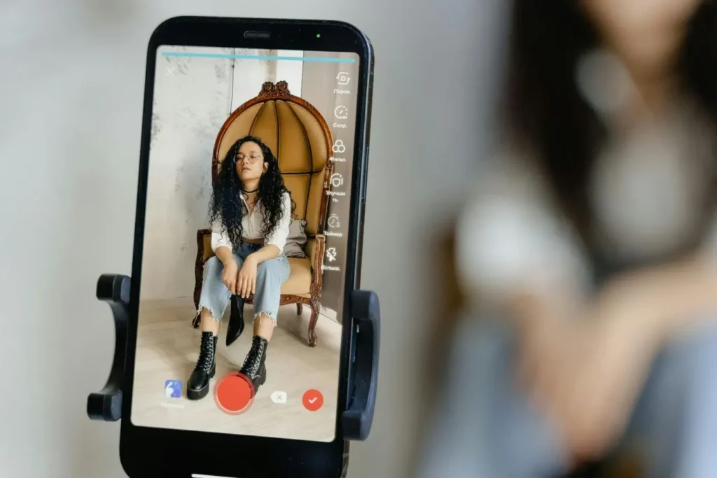 Smartphone filmant une personne assise sur chaise décorative, image illustrant la création de contenu et les opportunités de monétiser un livestream.