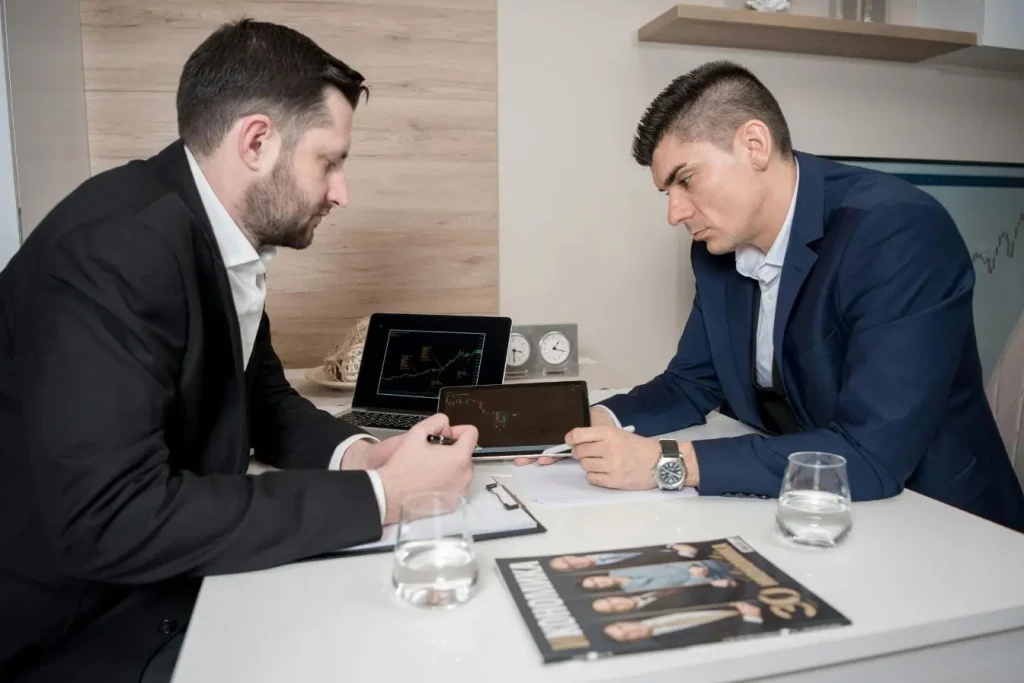 Deux professionnels discutent autour d’un bureau avec graphiques financiers, image d’un content marketing B2B axé sur données et stratégie.