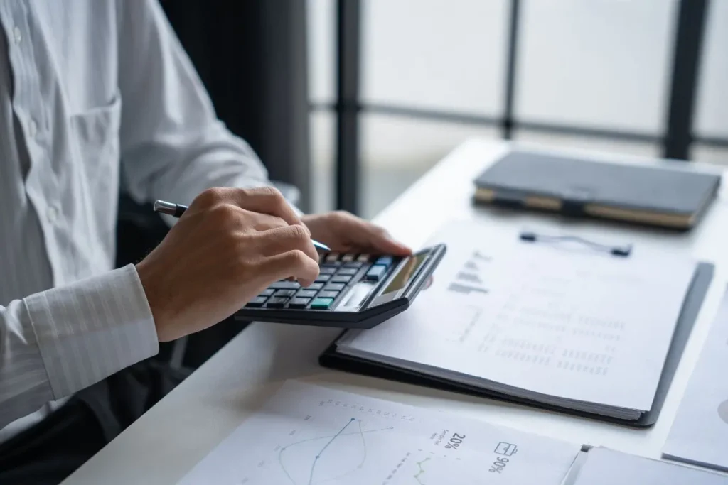 Personne utilisant calculatrice sur documents financiers reflétant l’analyse du Net Revenue Retention pour mesurer la croissance nette des revenus.