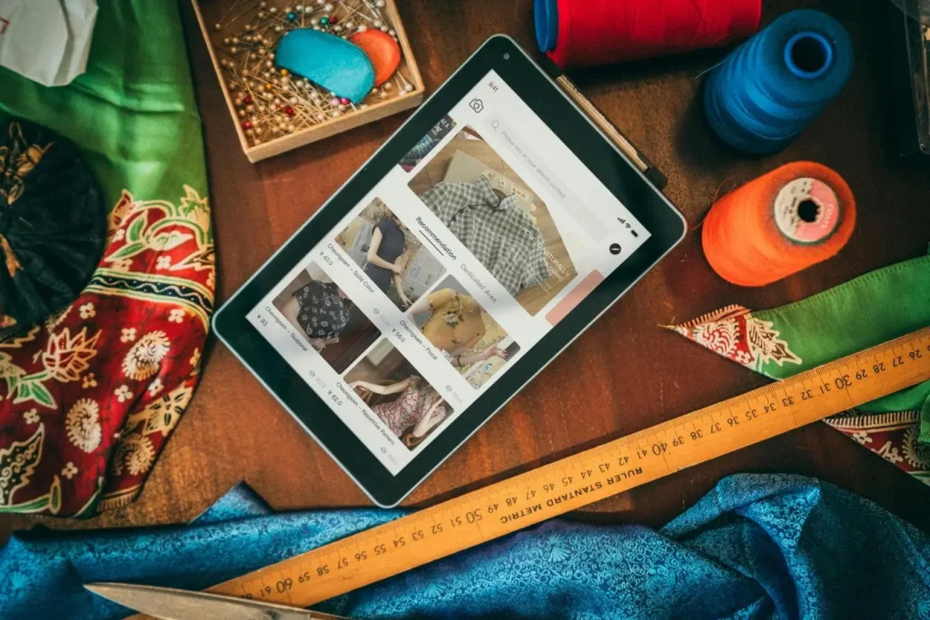 Table de couture avec tablette affichant boutique en ligne de vêtements, image représentant la création de sa marketplace pour artisans et créateurs.