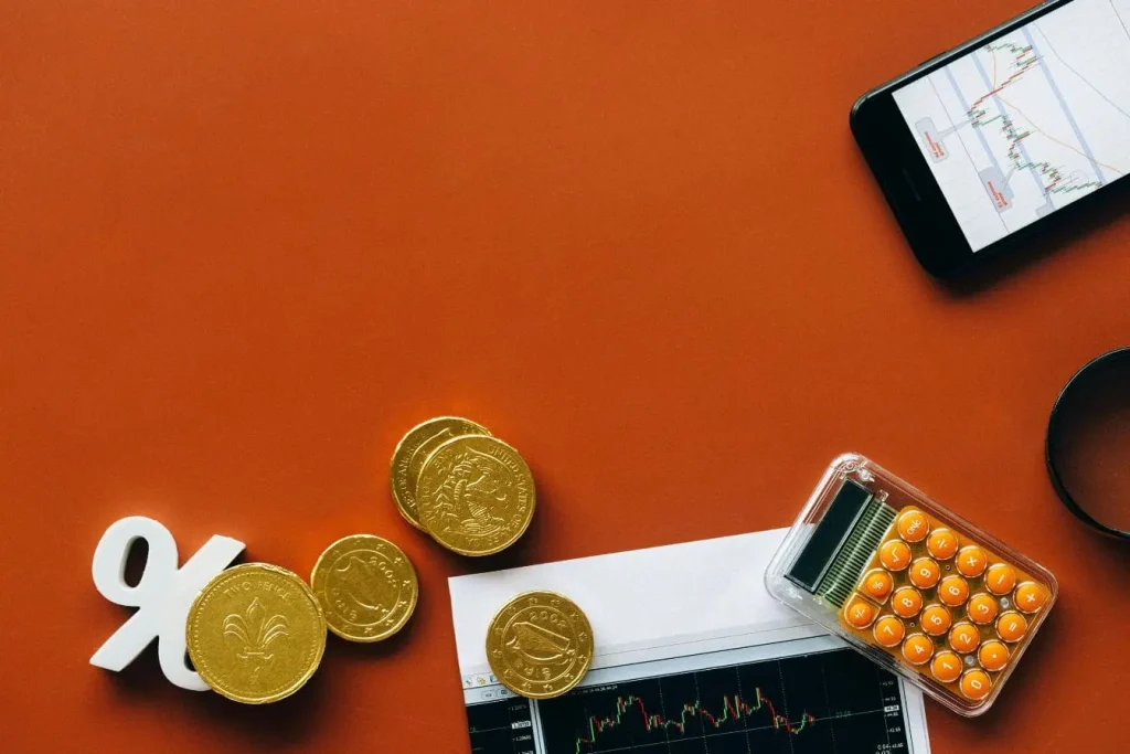 Pièces dorées, smartphone et graphique boursier illustrant la valeur créée par l’économie de plateforme et ses échanges numériques.
