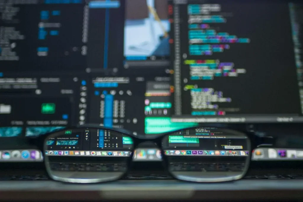 Gros plan sur écran avec code vu à travers lunettes, image illustrant la précision et l’efficacité du programmatic advertising.