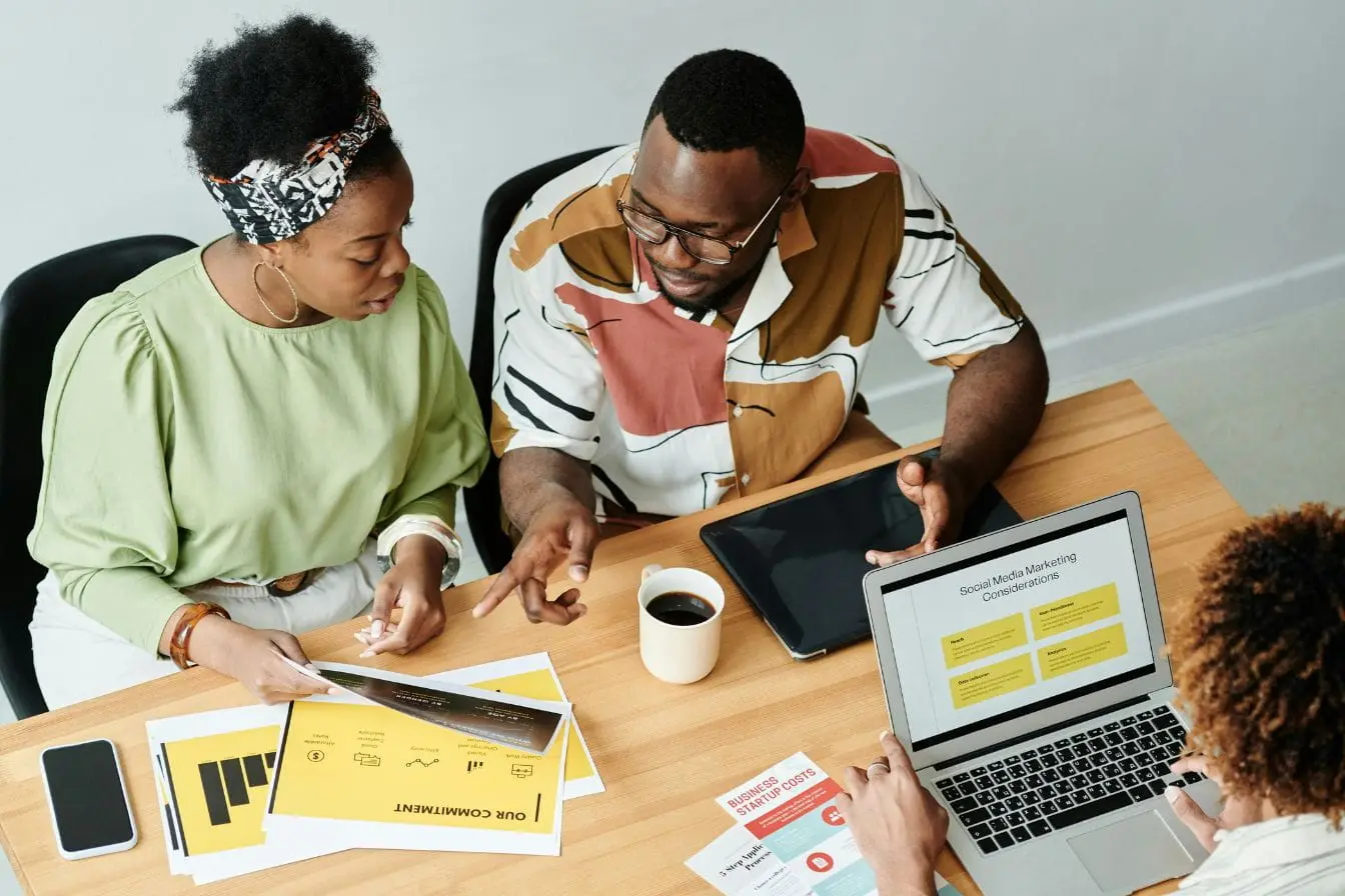 marketing conversationnel Réunion autour d’un laptop où trois collègues échangent des idées simples et directes pour engager les clients via le marketing conversationnel.