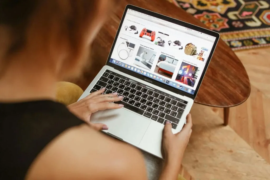 Personne utilisant MacBook Pro affichant site marchand avec catégories variées, image représentant la création de sa marketplace pour vendre en ligne.