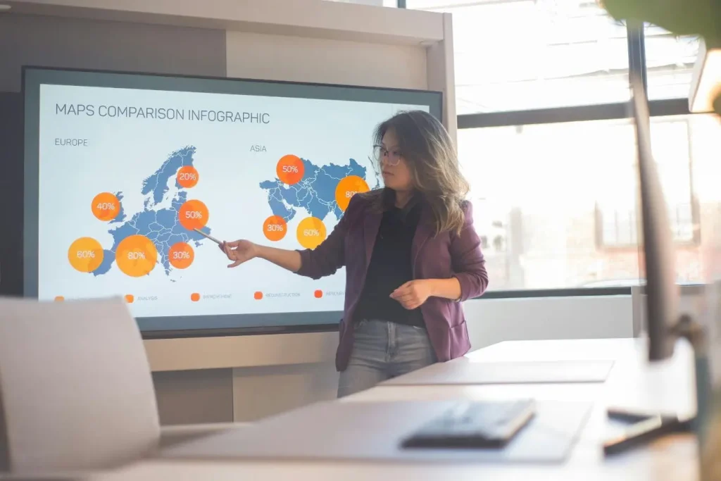Personne présentant carte comparative Europe et Asie avec cercles colorés, image illustrant un pitch deck visuel pour convaincre investisseurs.