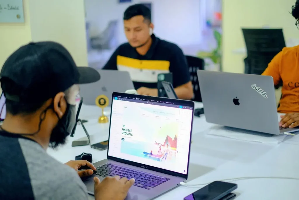 Trois personnes travaillent sur ordinateurs portables dans un bureau collaboratif, illustrant l’usage d’outils SaaS pour la création et le design numérique.
