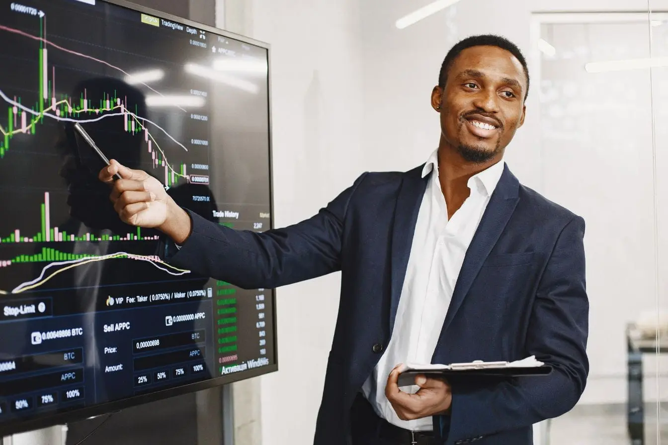 Personne en costume analysant graphiques financiers sur grand écran, image qui illustre l’usage de la Business Intelligence pour comprendre les tendances.