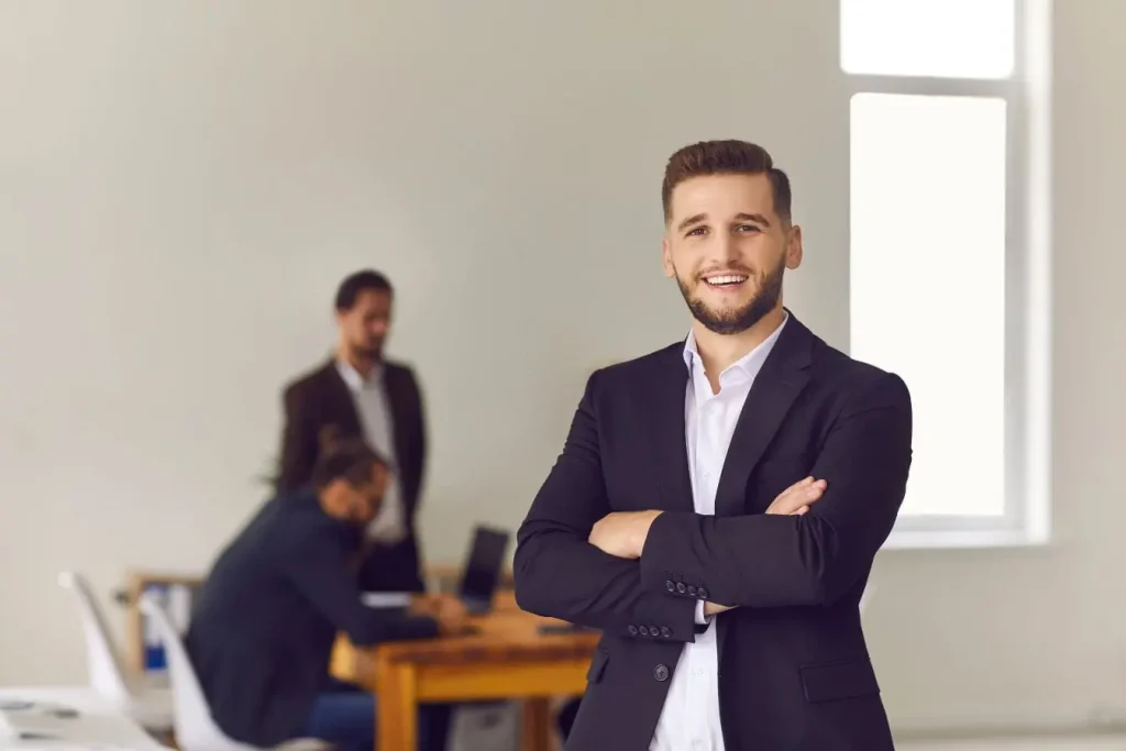Professionnel en costume croisé devant fenêtre, image illustrant la distinction entre rôle opérationnel du Product Owner et stratégique du Product Manager.
