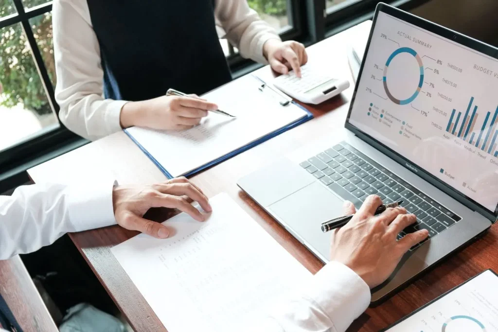 Deux personnes analysent graphiques budget et dépenses sur laptop, image illustrant l’attribution marketing multi-touch et la répartition des conversions.