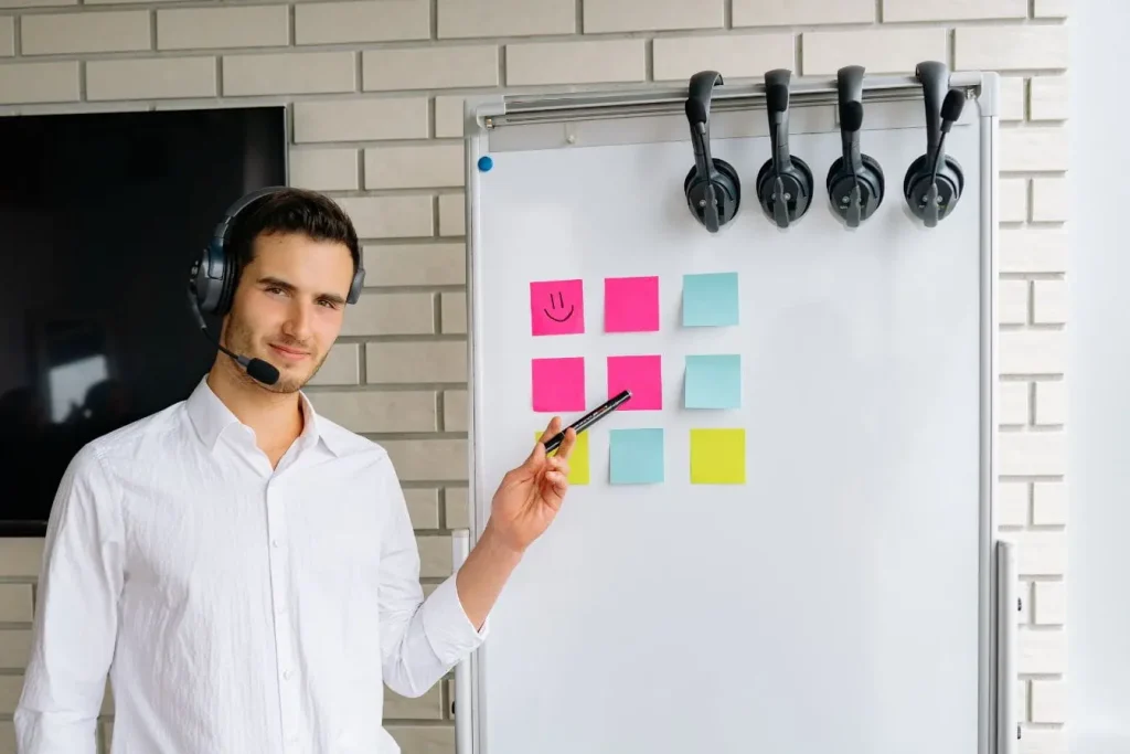Personne en chemise blanche pointe des post-it colorés sur tableau, image illustrant une product roadmap visuelle et collaborative.