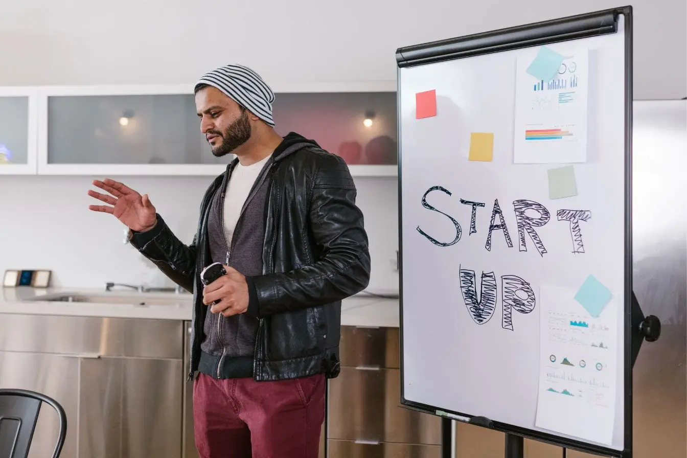 startup Personne devant tableau blanc marqué START UP avec notes colorées, image qui illustre l’idée de pivoter une startup pour trouver une nouvelle direction.