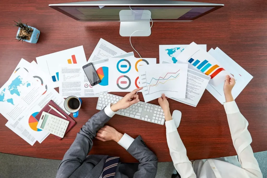 Bureau avec graphiques colorés et cartes du monde, image qui illustre la Business Intelligence pour analyser et comparer les données.