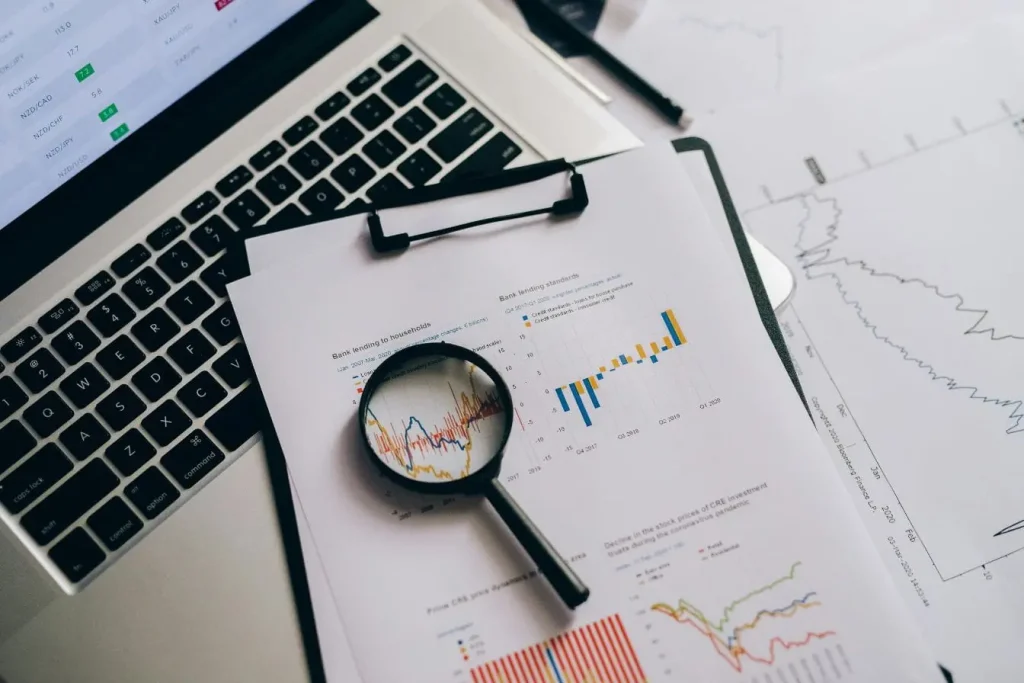 Bureau avec ordinateur portable et graphiques financiers imprimés, image qui illustre l’analyse des données issue d’un processus ETL.