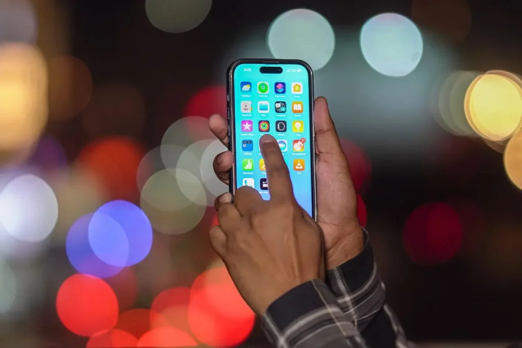 Gros plan sur main tenant smartphone affichant icônes colorées, image qui illustre la réflexion entre GraphQL et REST pour concevoir une API adaptée.