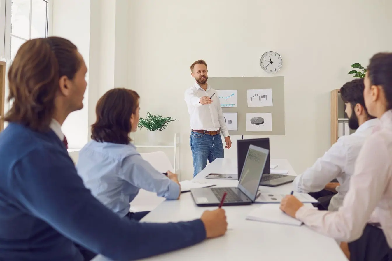 Réunion d’équipe Réunion d’équipe avec présentation de graphiques, image qui illustre la comparaison entre Inbound Sales et Outbound Sales dans un cadre professionnel.