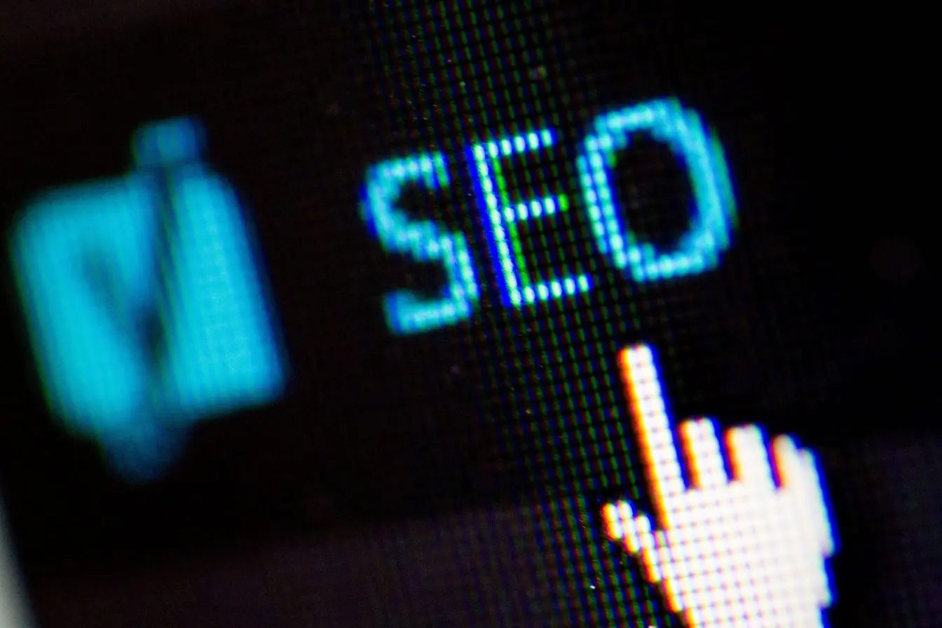 Gros plan sur écran affichant SEO en bleu avec curseur, reflet d’une stratégie digitale comparant SEO et SEA.