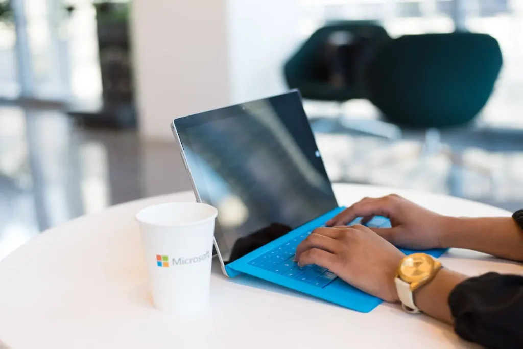 Personne tapant sur tablette Surface avec clavier bleu, image qui illustre la fluidité et l’automatisation d’un CI/CD pipeline en environnement moderne.