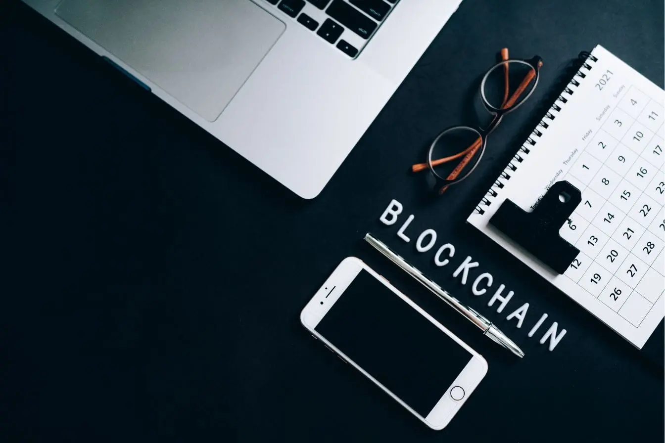 Vue d’un bureau moderne avec ordinateur portable et smartphone, image qui illustre l’univers numérique et l’importance de la blockchain.