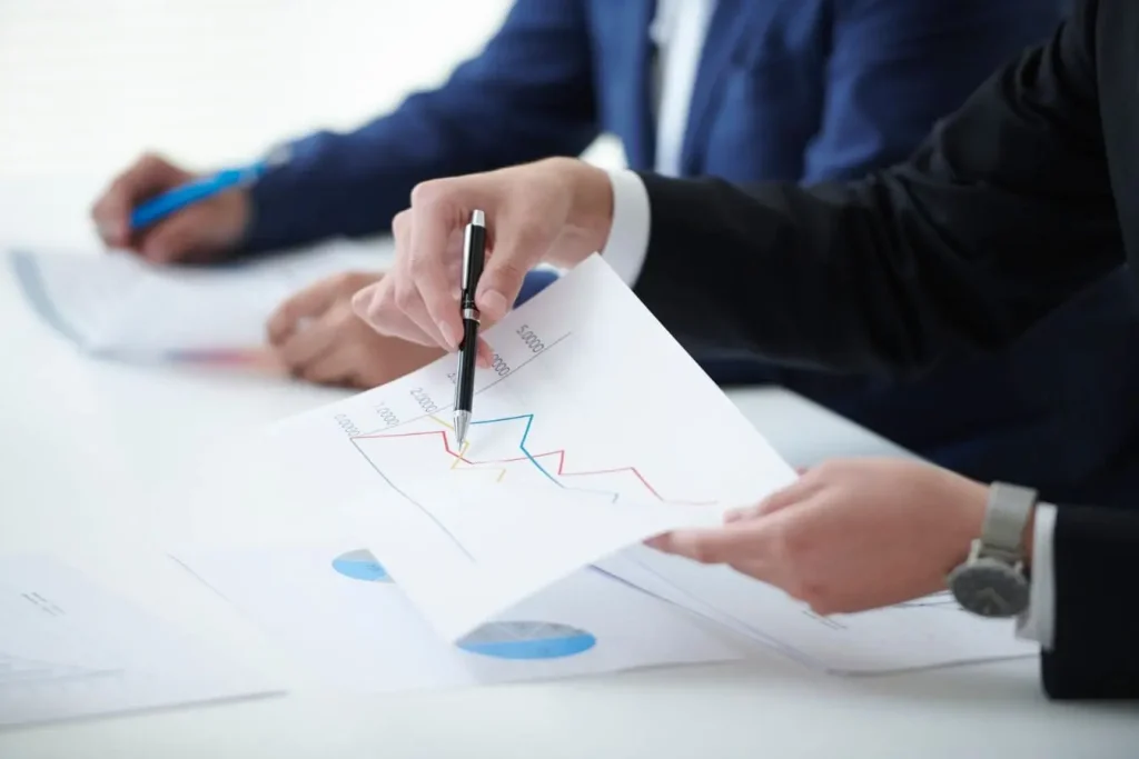 Deux collègues en réunion analysant graphiques imprimés, image qui illustre la comparaison entre Inbound Sales et Outbound Sales.