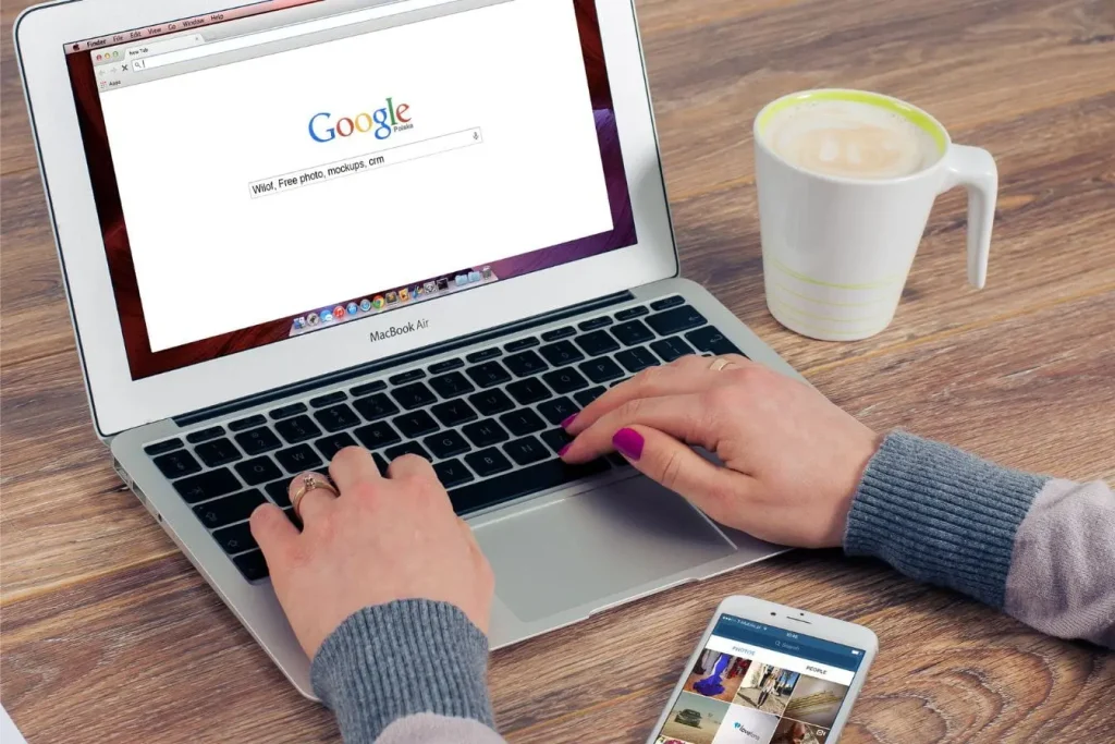 Personne tapant une recherche Google sur laptop, image qui illustre l’affichage d’un featured snippet en haut des résultats.