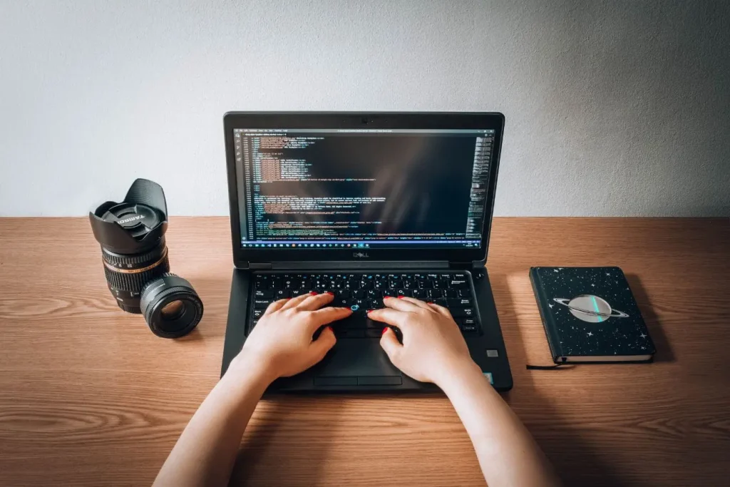 Personne tapant sur laptop Dell affichant du code, image qui illustre le principe du serverless computing où l’infrastructure est gérée automatiquement.