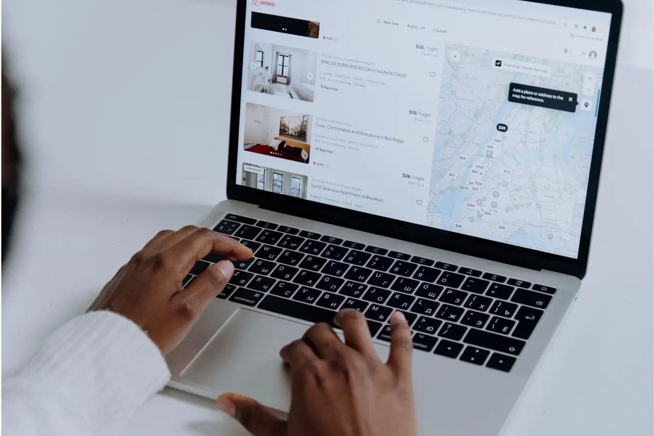 Écran d’ordinateur affichant Airbnb avec annonces et carte, reflet d’un site nécessitant optimisation du temps de chargement pour une meilleure expérience.