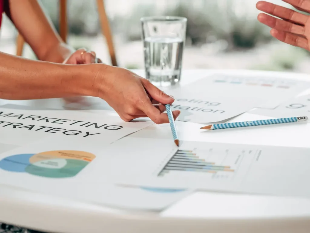 Deux personnes discutent autour de documents marketing, image d’un marketing sensoriel qui associe données et émotions pour capter l’attention.