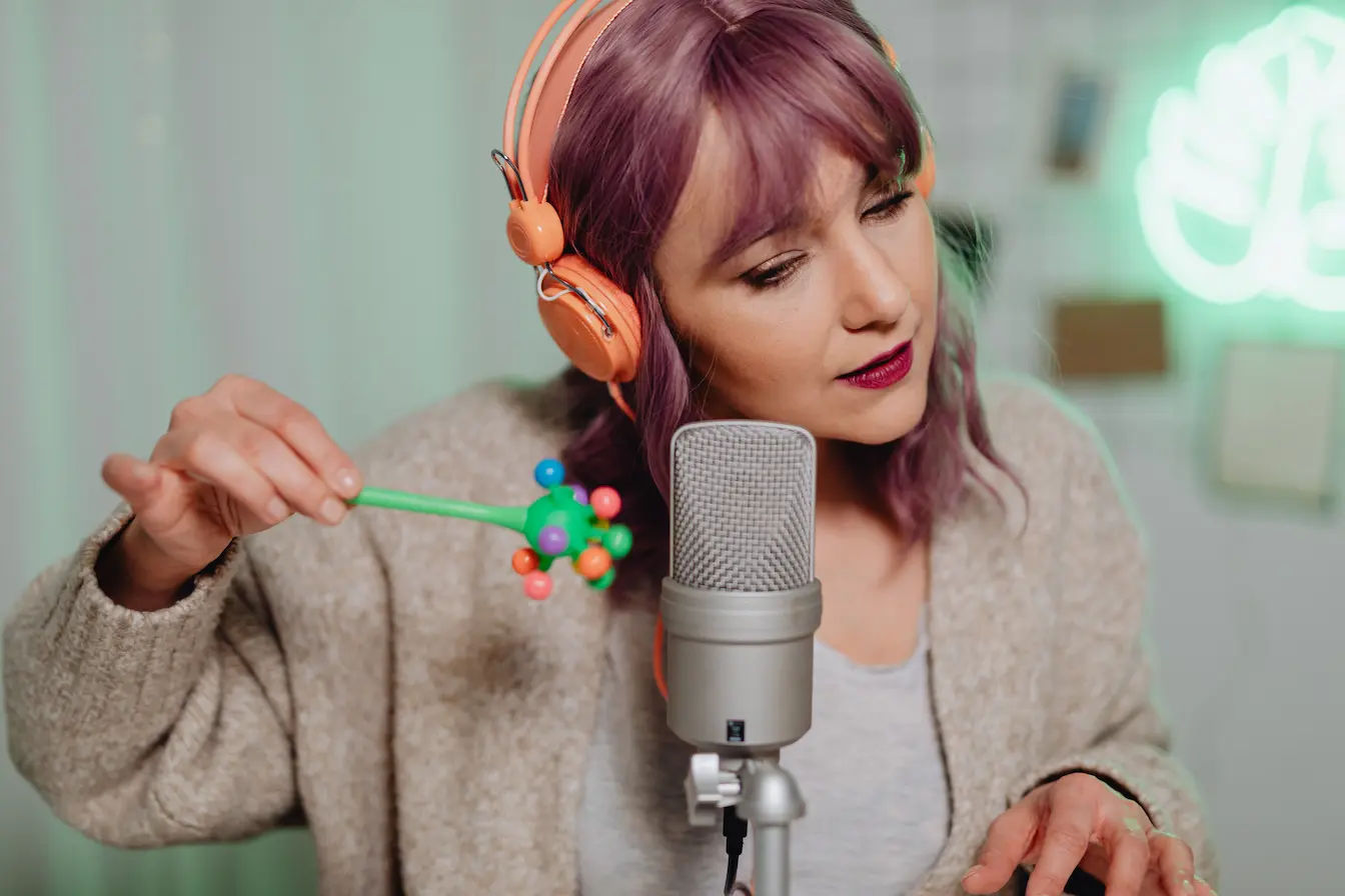 marketing sensoriel Personne avec casque orange et micro argenté, jouant avec un objet coloré, image d’une expérience de marketing sensoriel axée sur le son et la vue.