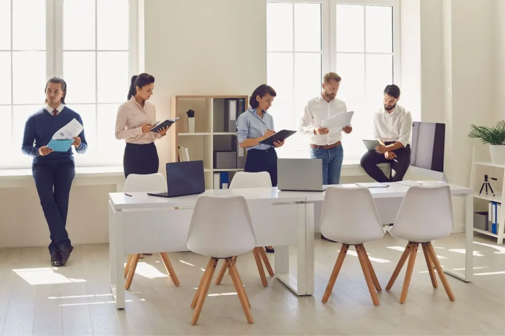 Équipe de collaborateurs analysant des documents et des dossiers dans un bureau lumineux, illustrant l’affacturage comme solution pour améliorer la trésorerie d’une entreprise