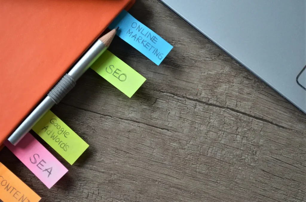 Carnet orange avec post‑it colorés mentionnant SEO et marketing, symbole d’une stratégie de contenu pilier bien organisée.