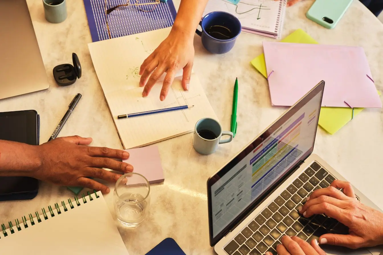 affacturage pour une entreprise Réunion de travail autour d’ordinateurs portables, de notes et de documents financiers, illustrant le recours à l’affacturage pour améliorer la trésorerie d’une entreprise