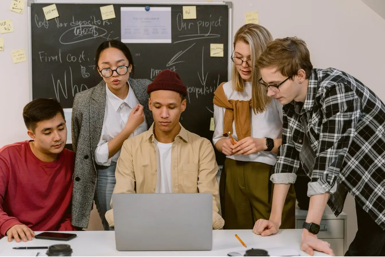 Équipe de créateurs d’entreprise réunie autour d’un ordinateur pour préparer un projet entrepreneurial, illustrant les démarches pour obtenir un prêt d’honneur